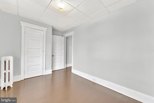 empty room featuring a drop ceiling and dark hardwood / wood-style flooring