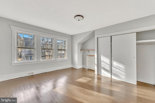 additional living space featuring radiator heating unit and hardwood / wood-style flooring