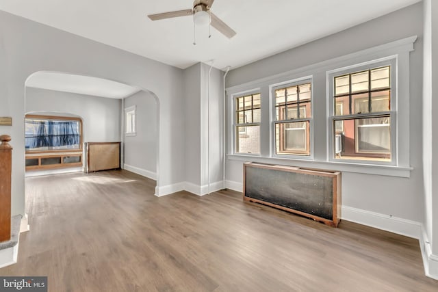 empty room with ceiling fan, wood-type flooring, and radiator heating unit