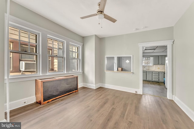 unfurnished living room featuring radiator heating unit, cooling unit, hardwood / wood-style flooring, and ceiling fan