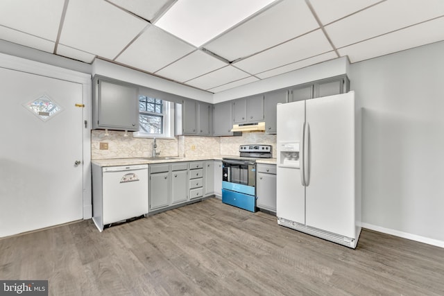 kitchen featuring a paneled ceiling, backsplash, light wood-type flooring, sink, and white appliances