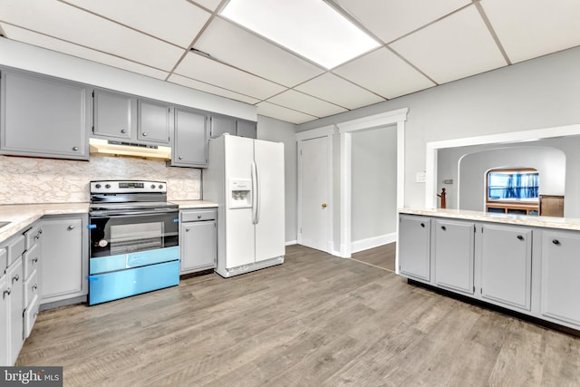 kitchen featuring white fridge with ice dispenser, gray cabinetry, a drop ceiling, and stainless steel range with electric stovetop