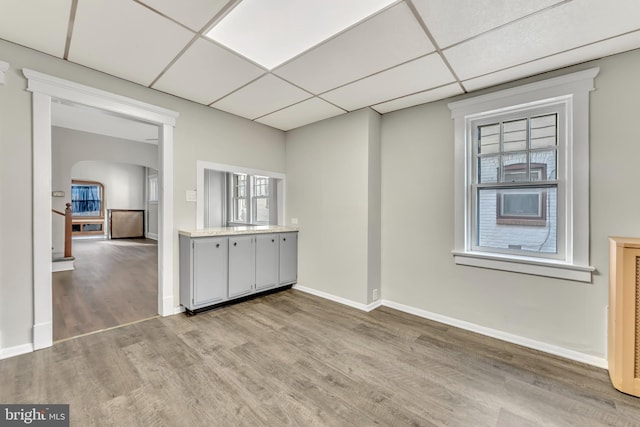 interior space featuring gray cabinetry, a drop ceiling, and light hardwood / wood-style flooring