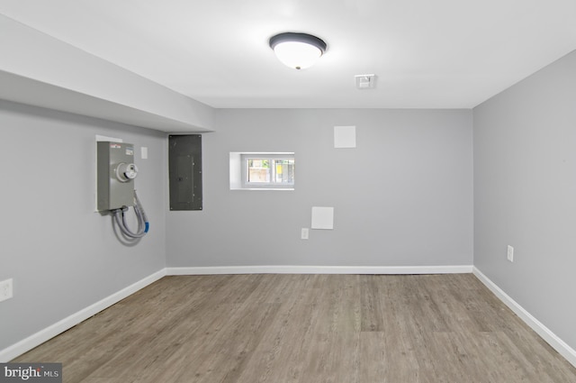 basement with electric panel and light hardwood / wood-style flooring