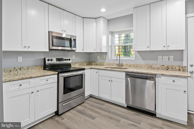 1106 Mckean Ave, Baltimore, MD 21217 - kitchen featuring appliances with stainless steel finishes, a sink, white cabinets, light wood-style floors, and recessed lighting