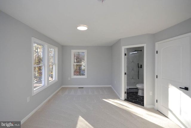 unfurnished bedroom featuring light colored carpet and connected bathroom