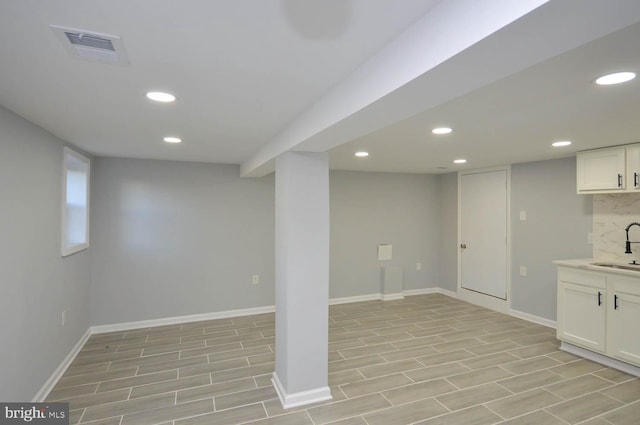 basement featuring sink and light hardwood / wood-style flooring