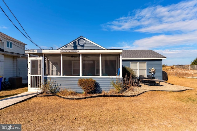 view of front facade with a front yard, a sunroom, and central AC