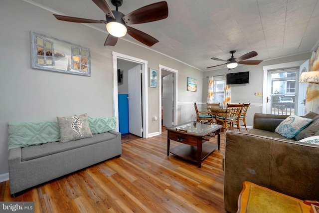 living room with ornamental molding, wood-type flooring, and ceiling fan