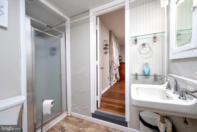 bathroom featuring hardwood / wood-style floors, walk in shower, sink, and toilet