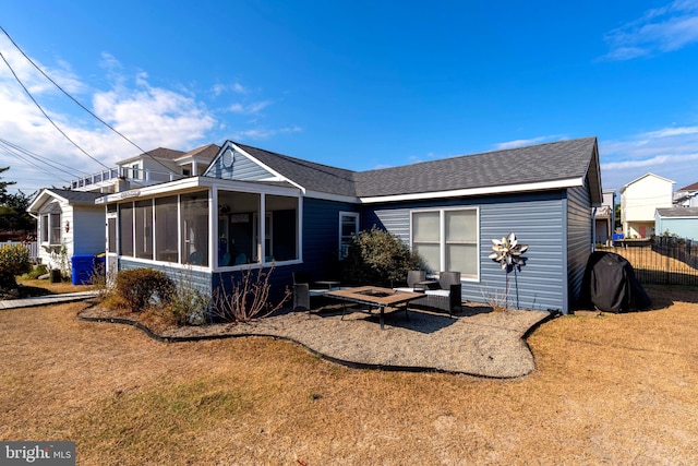 rear view of house featuring a sunroom and a yard