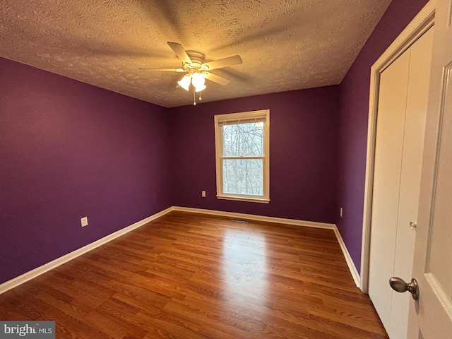 empty room featuring wood-type flooring, a textured ceiling, and ceiling fan