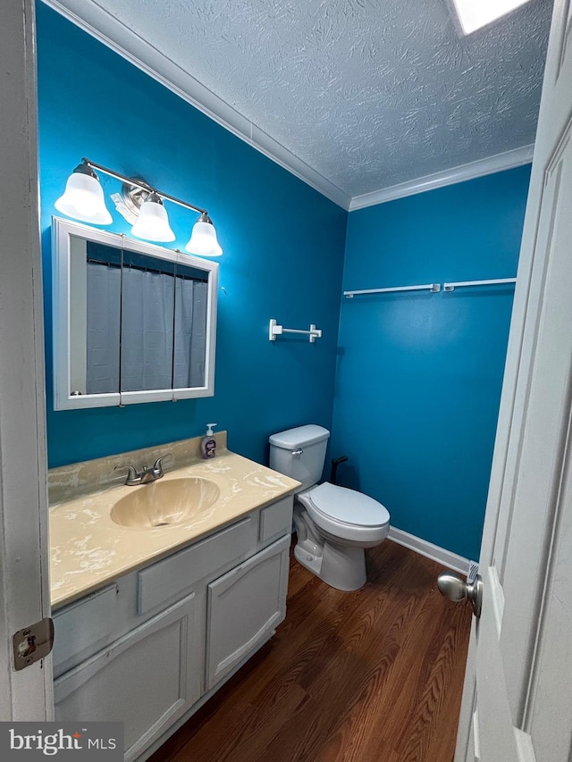 bathroom with crown molding, wood-type flooring, a textured ceiling, toilet, and vanity