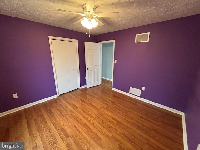 unfurnished bedroom featuring ceiling fan, wood-type flooring, a textured ceiling, and a closet