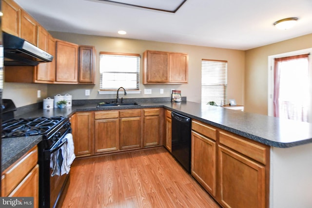 kitchen featuring sink, extractor fan, black appliances, kitchen peninsula, and light hardwood / wood-style flooring