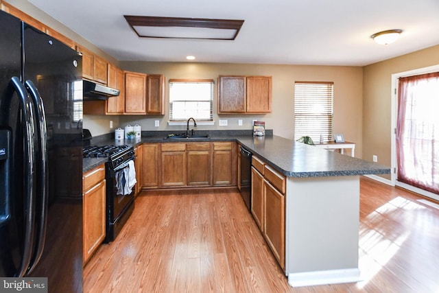 kitchen with light hardwood / wood-style floors, sink, black appliances, and kitchen peninsula