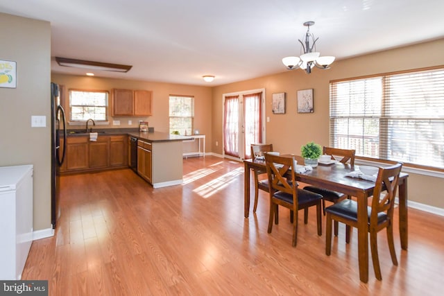 dining room with an inviting chandelier, sink, and light wood-type flooring