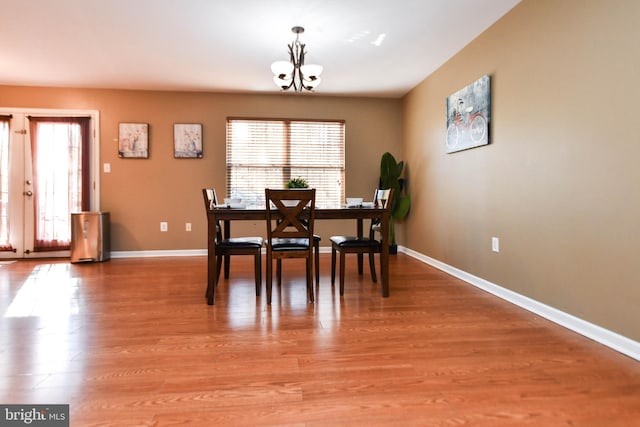 dining space with french doors, a notable chandelier, and light hardwood / wood-style flooring