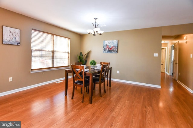 dining room with hardwood / wood-style floors and a chandelier