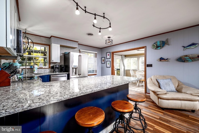 kitchen with light stone countertops, a kitchen breakfast bar, stainless steel appliances, dark hardwood / wood-style floors, and white cabinetry