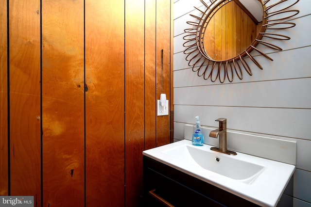 bathroom featuring vanity and wood walls