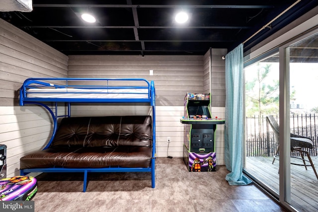 bedroom featuring access to outside and wooden walls