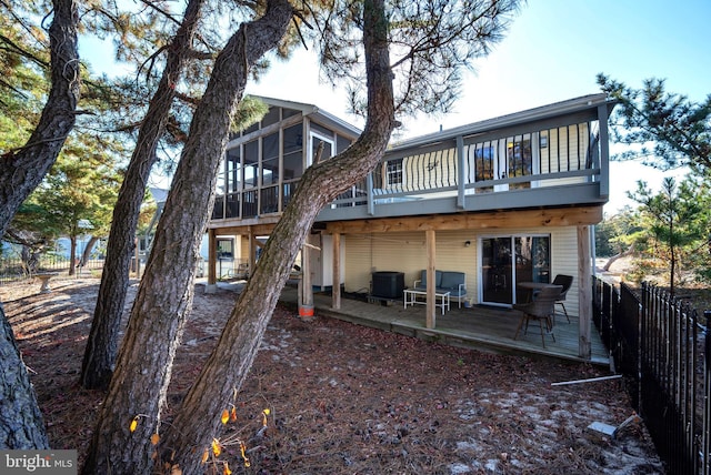 back of property with a sunroom, a deck, and central AC