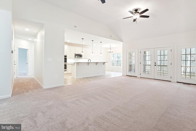 unfurnished living room with french doors, plenty of natural light, light carpet, and ceiling fan