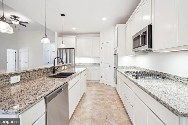 kitchen featuring stainless steel appliances, white cabinets, sink, an island with sink, and pendant lighting