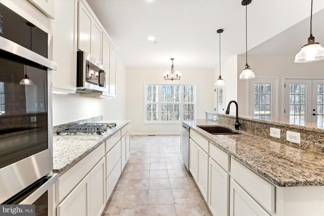 kitchen featuring stainless steel appliances, white cabinets, plenty of natural light, sink, and decorative light fixtures