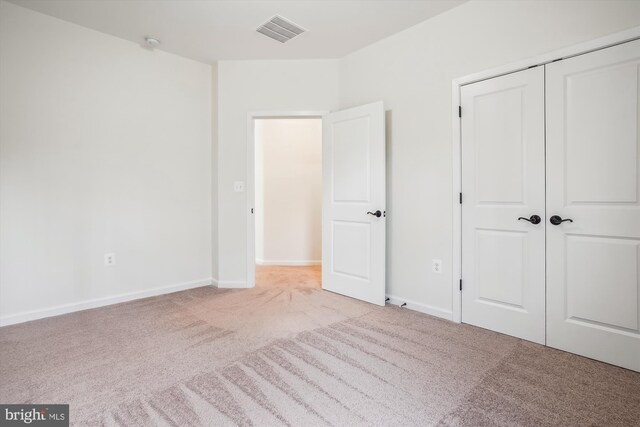 unfurnished bedroom with light carpet and a closet