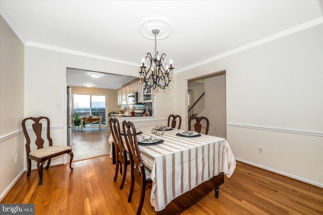 dining area with light hardwood / wood-style floors, a notable chandelier, and ornamental molding