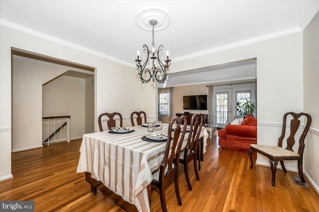 dining area with french doors, an inviting chandelier, crown molding, and hardwood / wood-style flooring