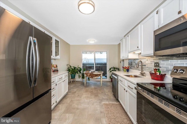 kitchen with appliances with stainless steel finishes, tasteful backsplash, white cabinetry, and sink