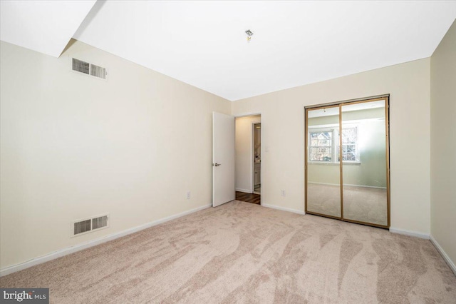 unfurnished bedroom featuring light colored carpet and a closet