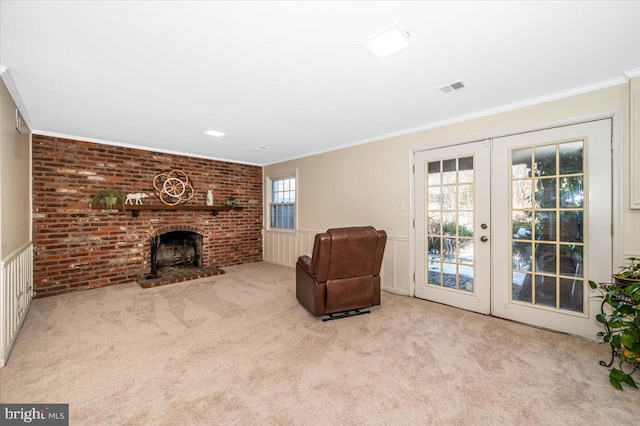 sitting room with french doors, a brick fireplace, ornamental molding, and light colored carpet