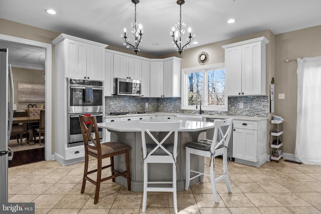 kitchen with a kitchen island, white cabinetry, a notable chandelier, and stainless steel appliances