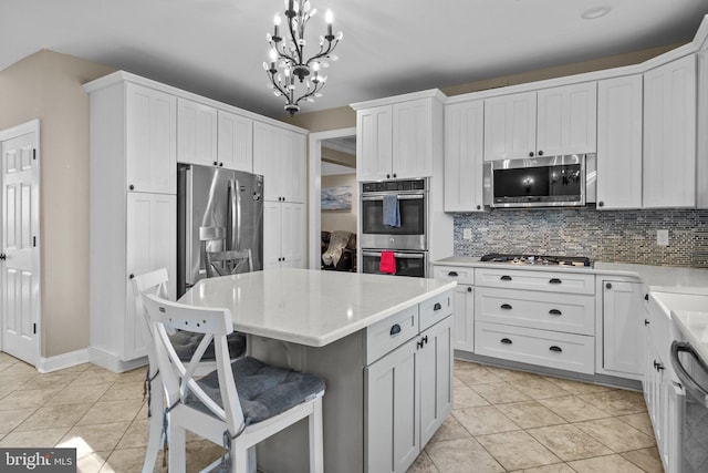 kitchen featuring stainless steel appliances, light tile patterned floors, a kitchen island, pendant lighting, and white cabinetry