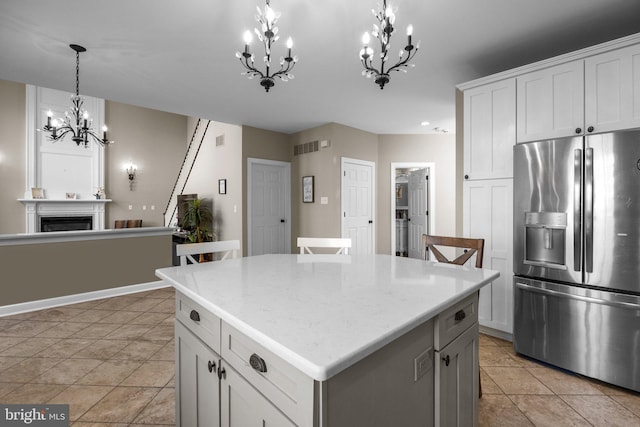 kitchen featuring light tile patterned flooring, white cabinetry, stainless steel refrigerator with ice dispenser, hanging light fixtures, and a center island