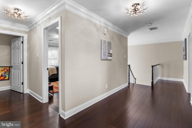 hall featuring dark wood-type flooring, an inviting chandelier, and crown molding