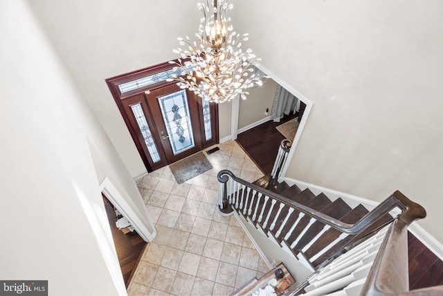 entryway with a notable chandelier, light tile patterned floors, and a high ceiling