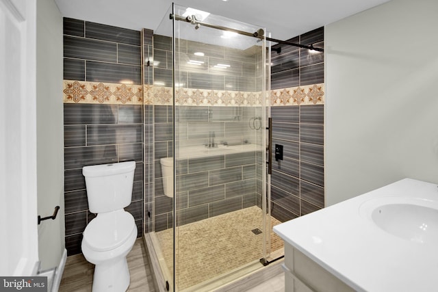 bathroom with toilet, vanity, an enclosed shower, and tile walls