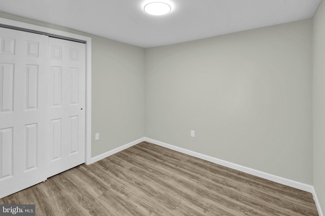 unfurnished bedroom featuring wood-type flooring and a closet