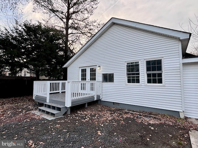 back house at dusk featuring a wooden deck