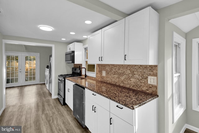 kitchen featuring appliances with stainless steel finishes, white cabinetry, french doors, dark stone counters, and tasteful backsplash