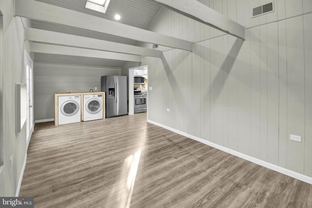 laundry room with hardwood / wood-style floors, wooden walls, and independent washer and dryer