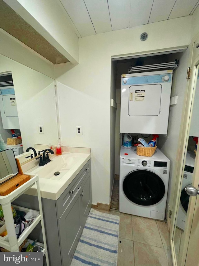 laundry area featuring sink, light tile patterned floors, and stacked washer and dryer