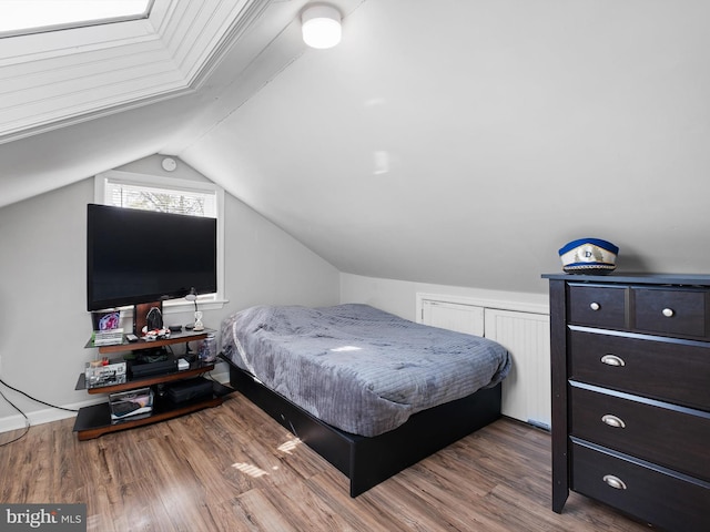 bedroom with wood-type flooring and vaulted ceiling