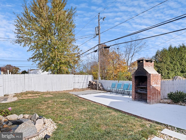 view of yard with an outdoor brick fireplace and a patio area