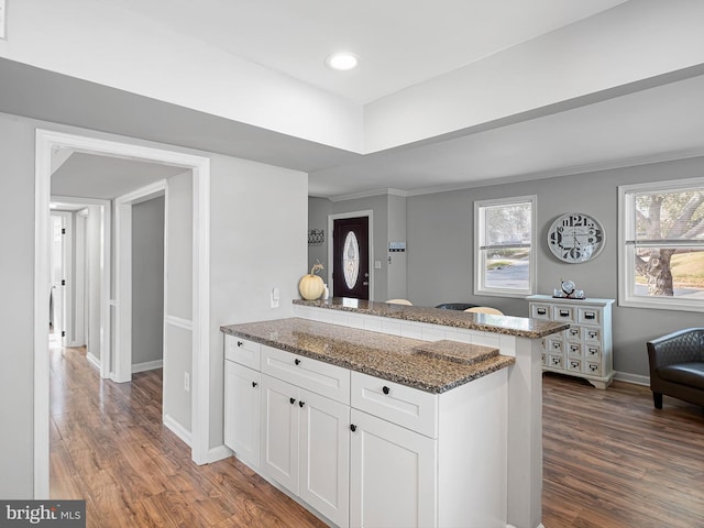 kitchen with white cabinets, kitchen peninsula, dark stone counters, and dark hardwood / wood-style floors